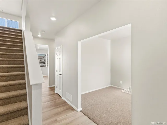 a view of a hallway with wooden floor and staircase
