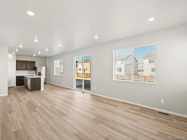 an empty room with wooden floor and a kitchen