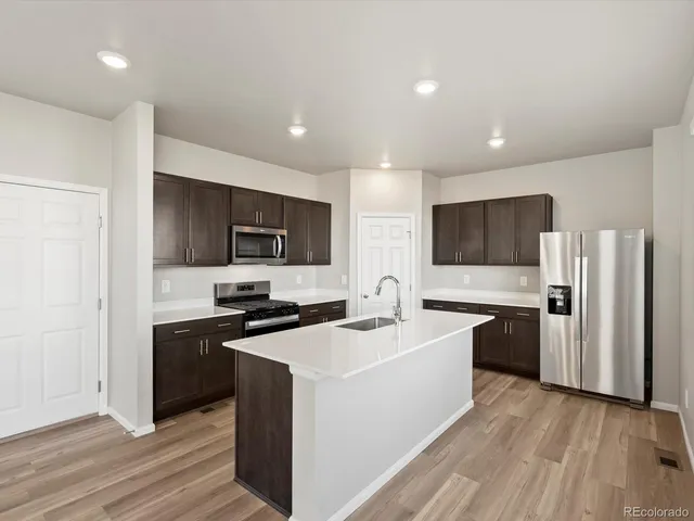 a kitchen with a sink a stove top oven a refrigerator cabinets and wooden floor