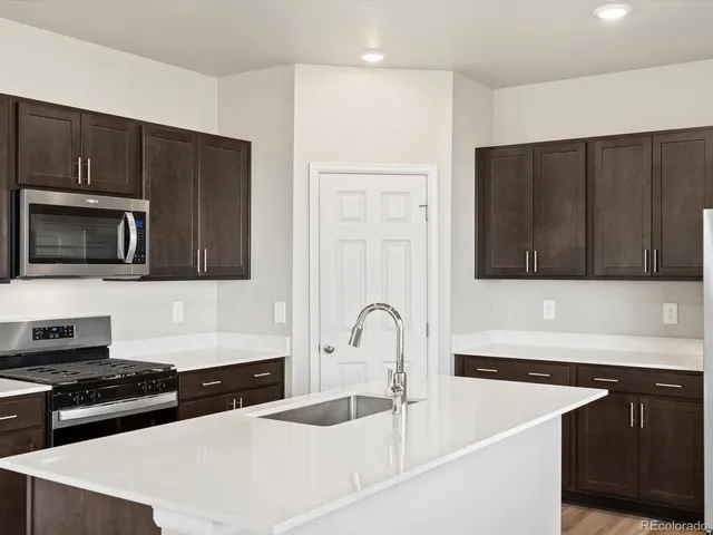a kitchen with stainless steel appliances a sink a stove a microwave a sink and cabinets