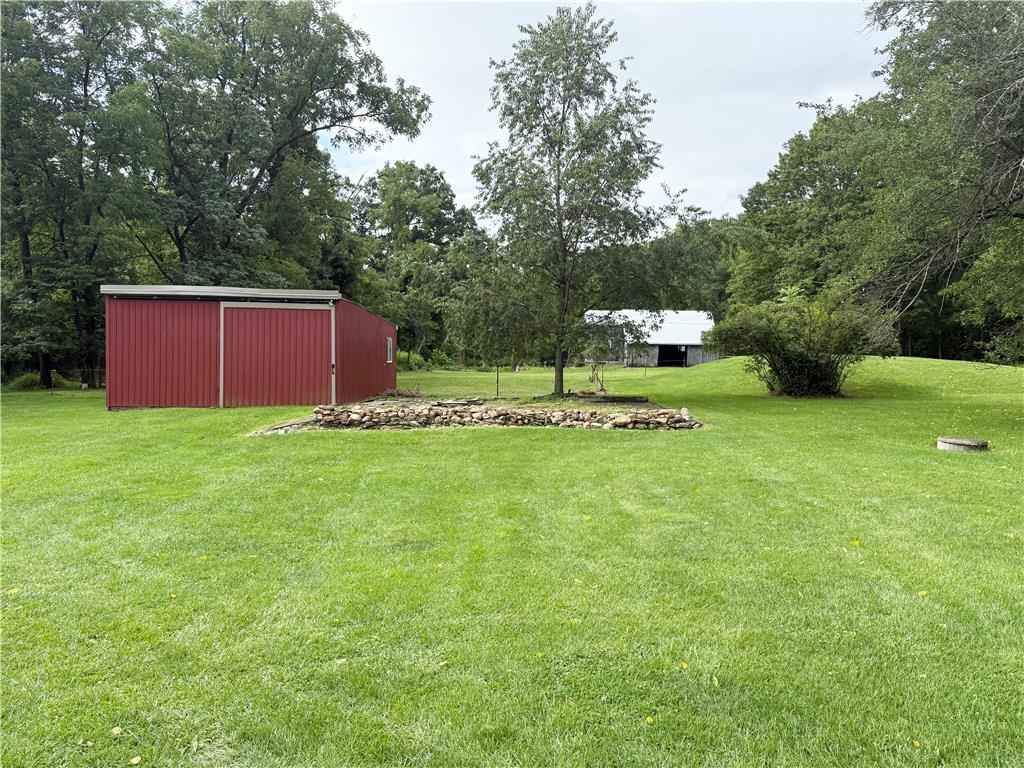 740 Engler Road Nazareth, PA 18064 - Photo 26 of 27 A spacious green lawn extends towards a red shed, with a distant barn nestled among mature trees.