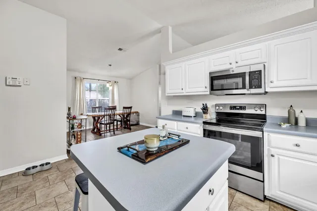 a kitchen with a stove a sink dishwasher a microwave oven with a dining table and chairs