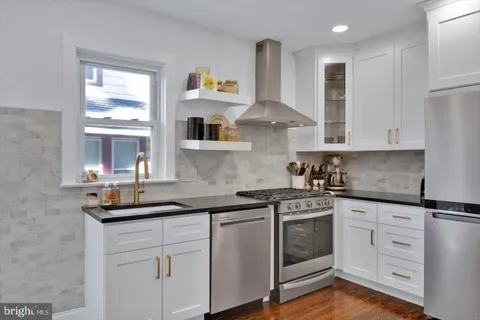 a kitchen with stainless steel appliances granite countertop a refrigerator sink and white cabinets