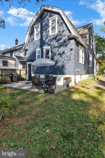 a view of backyard of house with wooden deck and outdoor seating