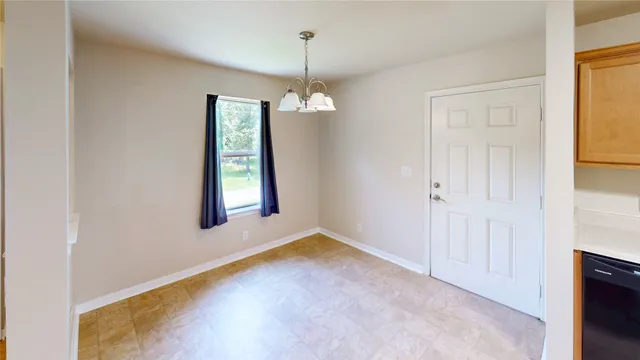 a view of an empty room with window and chandelier fan