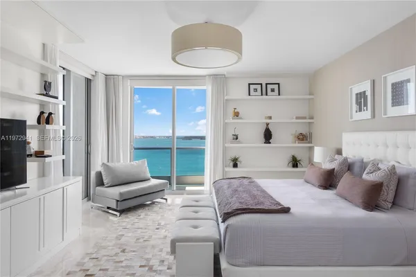 a bedroom with a bed a couch and large window