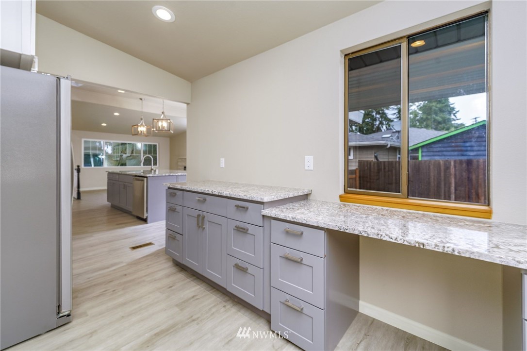 2926 Northeast 5th Place Renton, WA 98056 - Photo 12 of 40 a kitchen with stainless steel appliances granite countertop a sink and dishwasher with wooden floor