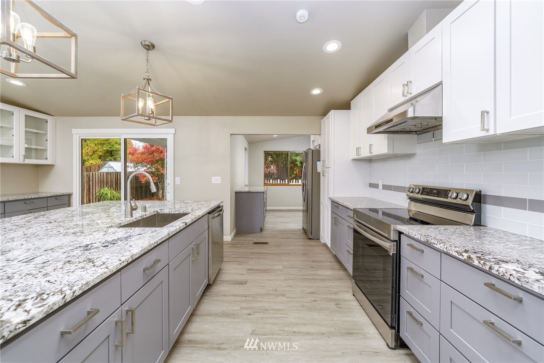2926 Northeast 5th Place Renton, WA 98056 - Photo 10 of 40 a kitchen with kitchen island granite countertop a sink a counter top space stainless steel appliances and cabinets