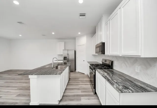 a kitchen with granite countertop a sink and a stove top oven
