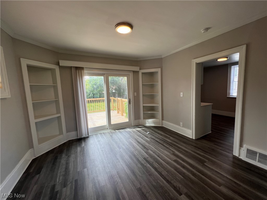 14807 Alger Road Cleveland, OH 44111 - Photo 4 of 16 Wood floored empty room with built in shelves and ornamental molding
