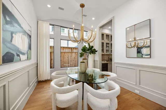 a dining room with wooden floor a chandelier a glass table and chairs