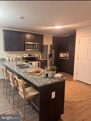 a kitchen with stainless steel appliances granite countertop a stove a sink a microwave a refrigerator and cabinets