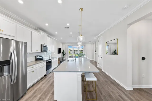 a large kitchen with kitchen island a large counter top space a sink stainless steel appliances and cabinets