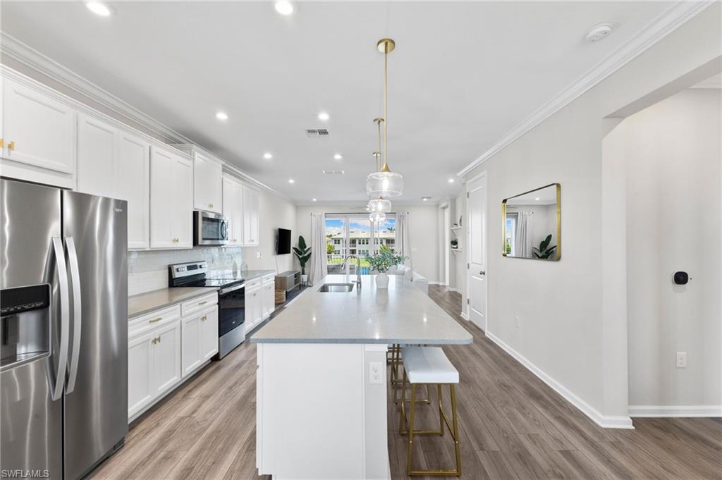 a large kitchen with kitchen island a large counter top space a sink stainless steel appliances and cabinets