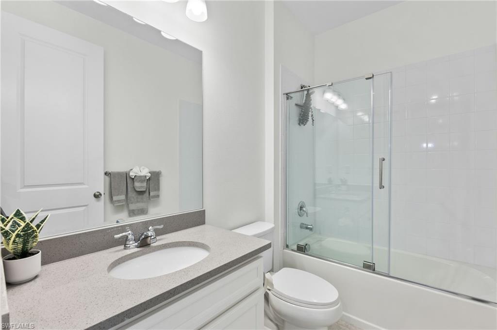4607 Arboretum Circle, Unit 202 Naples, FL 34112 - Photo 14 of 39 a bathroom with a granite countertop sink toilet a large mirror a shower and a bathtub