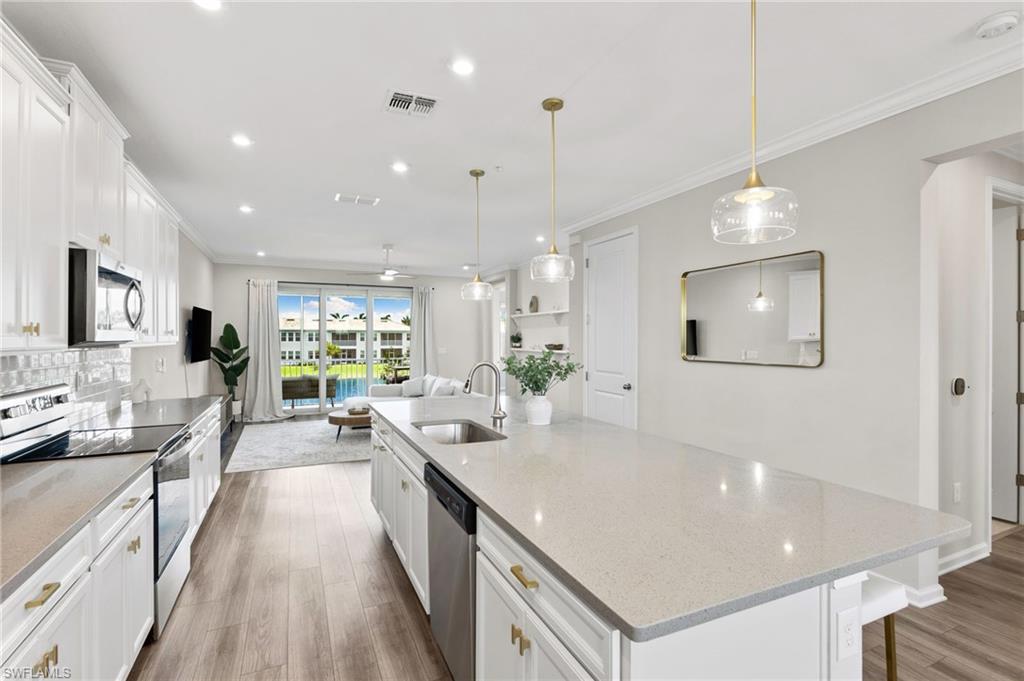 4607 Arboretum Circle, Unit 202 Naples, FL 34112 - Photo 15 of 39 a large kitchen with kitchen island a large island a sink stainless steel appliances and cabinets