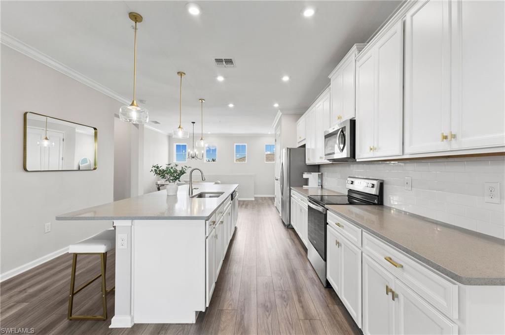 4607 Arboretum Circle, Unit 202 Naples, FL 34112 - Photo 23 of 39 a large kitchen with stainless steel appliances kitchen island granite countertop a lot of counter space and wooden floors