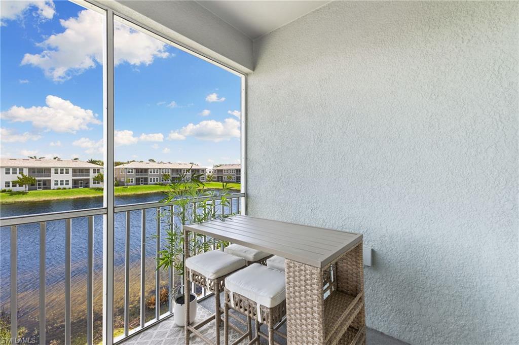 4607 Arboretum Circle, Unit 202 Naples, FL 34112 - Photo 31 of 39 a balcony with a table and chairs and wooden fence