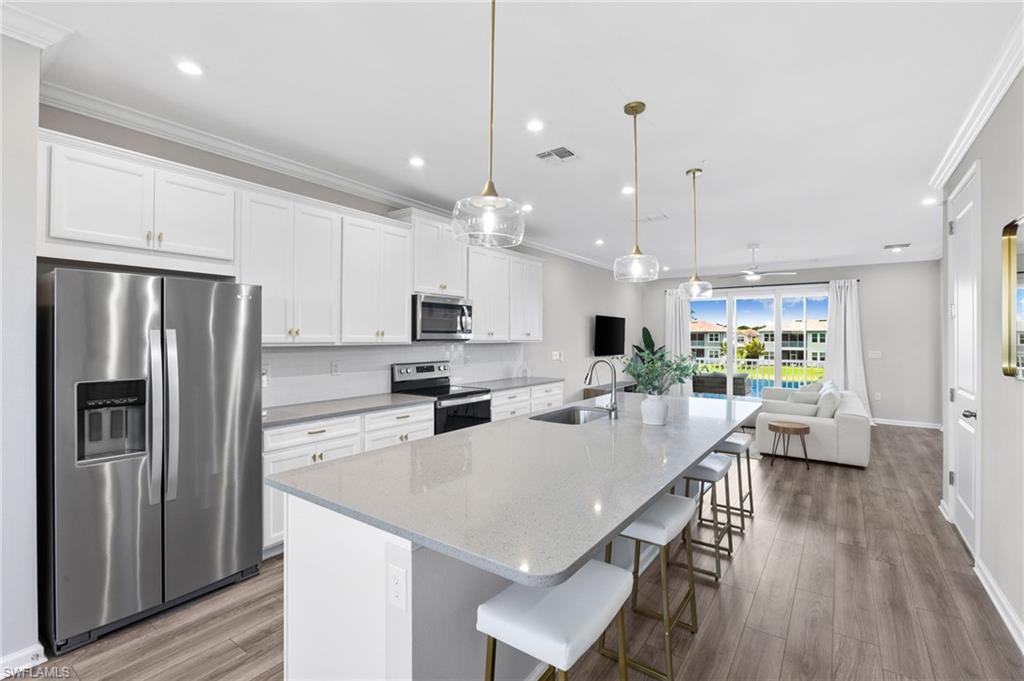 4607 Arboretum Circle, Unit 202 Naples, FL 34112 - Photo 5 of 39 a kitchen with stainless steel appliances granite countertop a refrigerator a sink dishwasher a stove and white cabinets with wooden floor