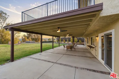 a view of a patio with table and chairs floor to ceiling window with wooden fence