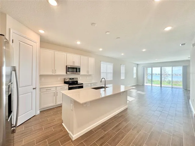 a kitchen with stainless steel appliances a sink stove top oven and white cabinets