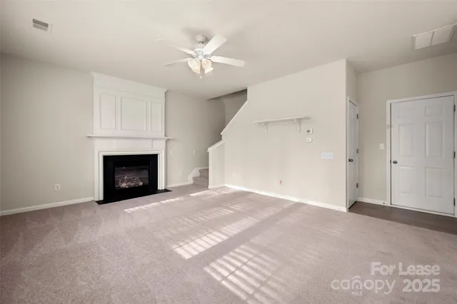 a view of an empty room and chandelier fan