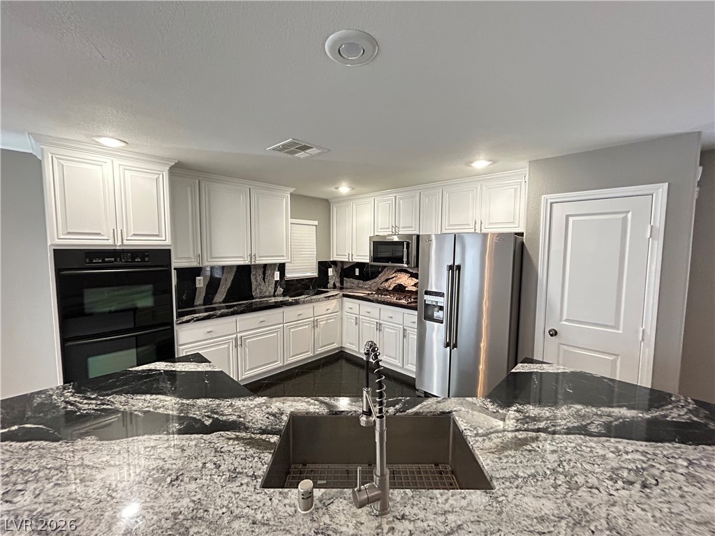 6538 Elm Spring Las Vegas, NV 89148 - Photo 3 of 29 White cabinetry complements dramatic black and white granite countertops in this functional kitchen.