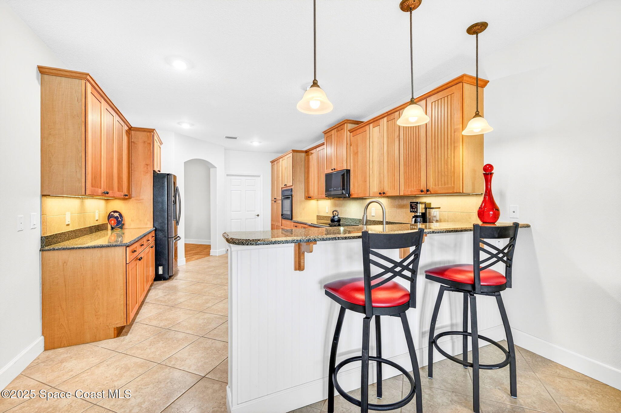 3407 Bancroft Drive Melbourne, FL 32940 - Photo 16 of 74 a kitchen with stainless steel appliances kitchen island granite countertop a refrigerator a stove a microwave oven with a dining table and chairs