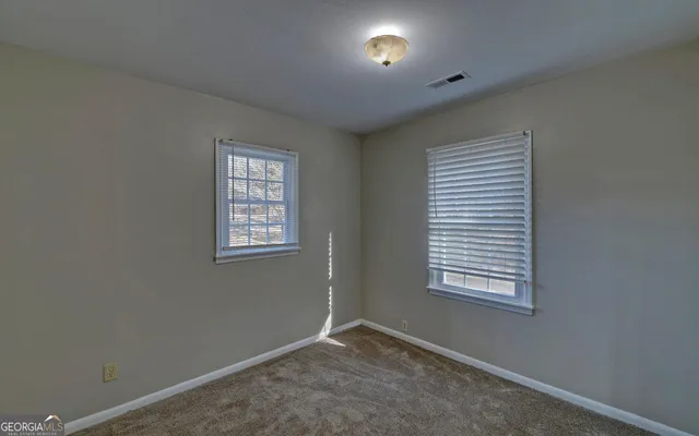 an empty room with chandelier fan and windows