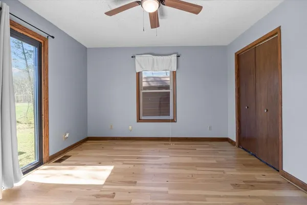 a view of an empty room with window and wooden floor