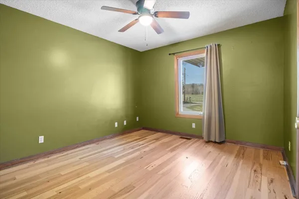 a view of a room with a ceiling fan and hardwood floor