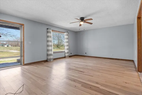 an empty room with wooden floor fan and windows