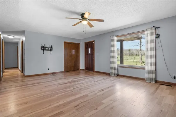 an empty room with wooden floor and windows