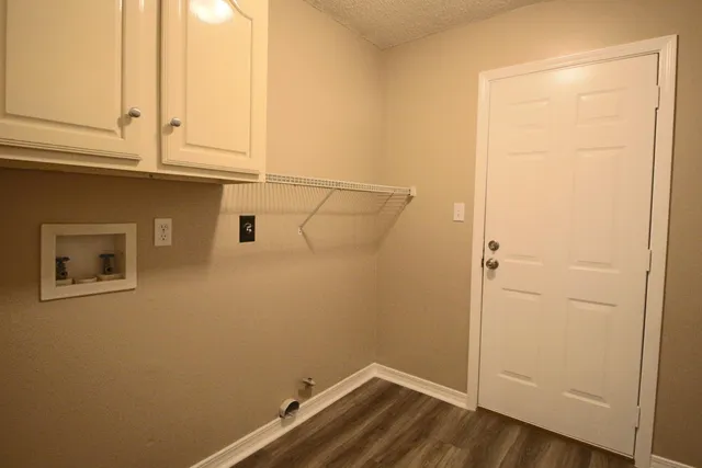a kitchen with granite countertop a stove a sink and white cabinets with wooden floor