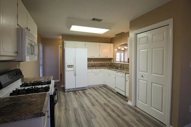 a kitchen with granite countertop white cabinets and refrigerator