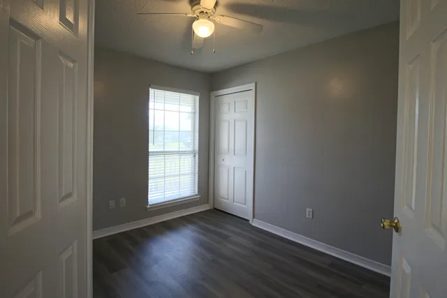 an empty room with wooden floor fireplace and windows