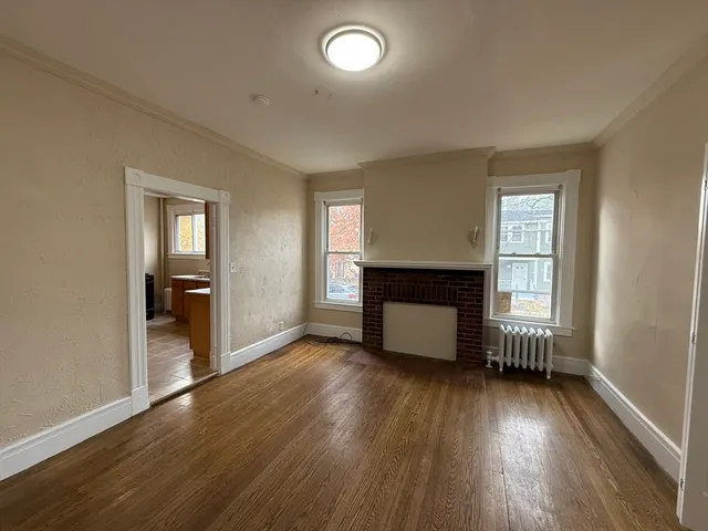 an empty room with wooden floor and fireplace