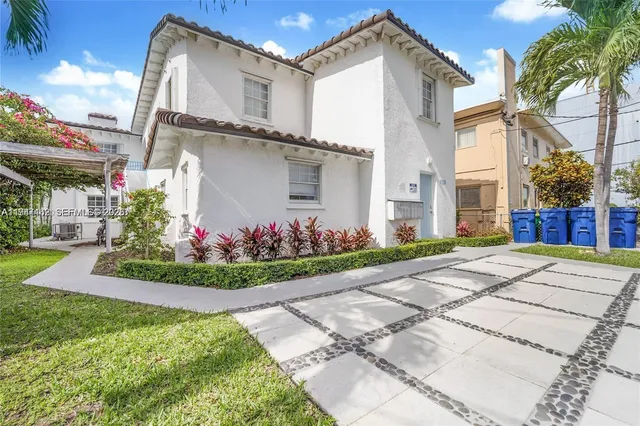 a front view of a house with a yard and potted plants