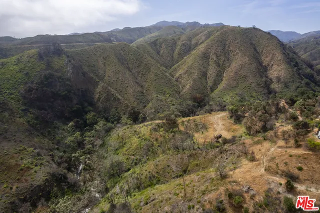 a view of a dry yard with mountains in the background