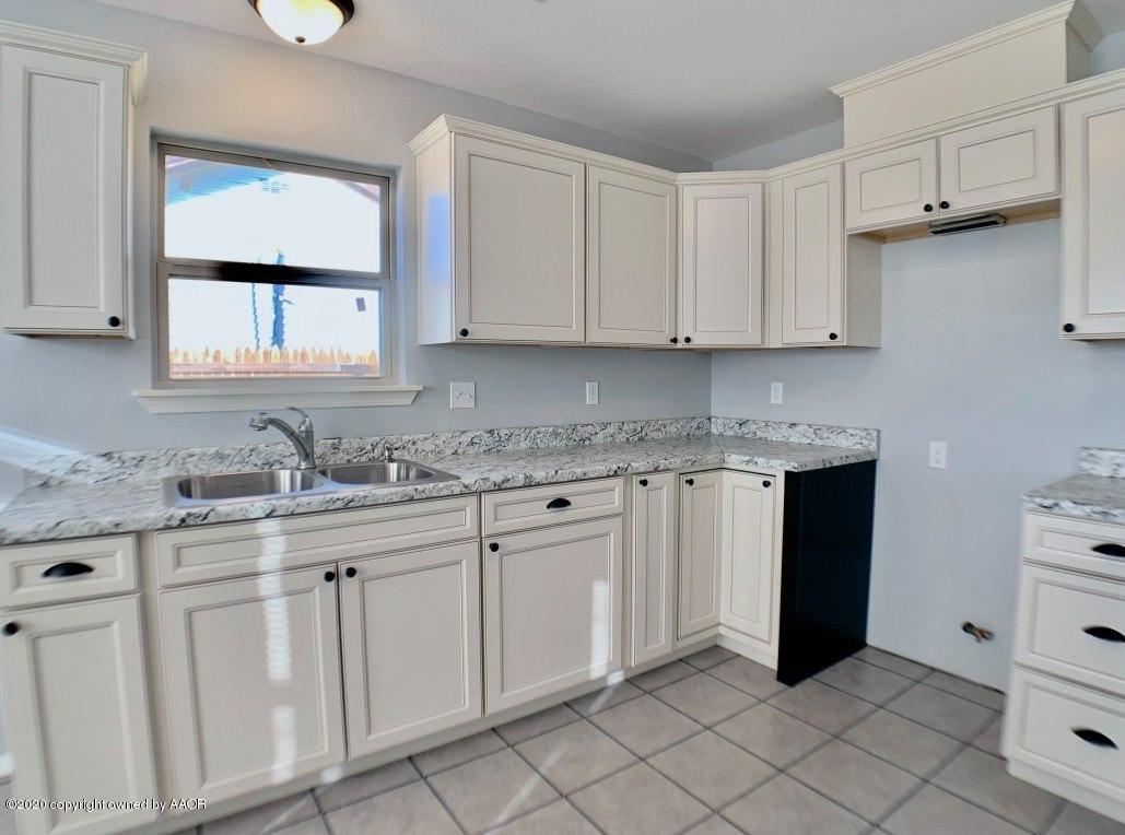 4213 South Harrison Street Amarillo, TX 79110 - Photo 3 of 14 a kitchen with granite countertop white cabinets and window
