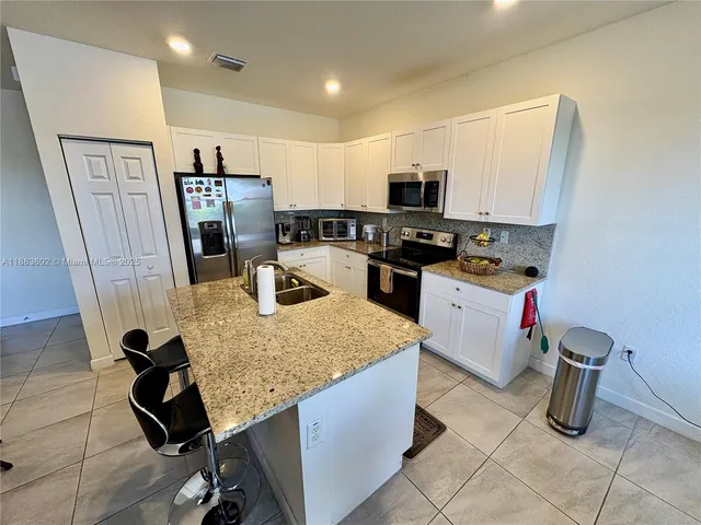 a kitchen with stainless steel appliances kitchen island granite countertop a sink dishwasher stove top oven and cabinets