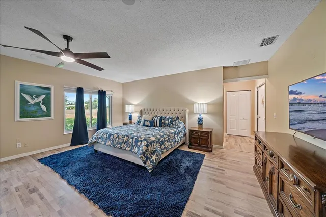 a spacious bedroom with a large bed a chandelier and windows