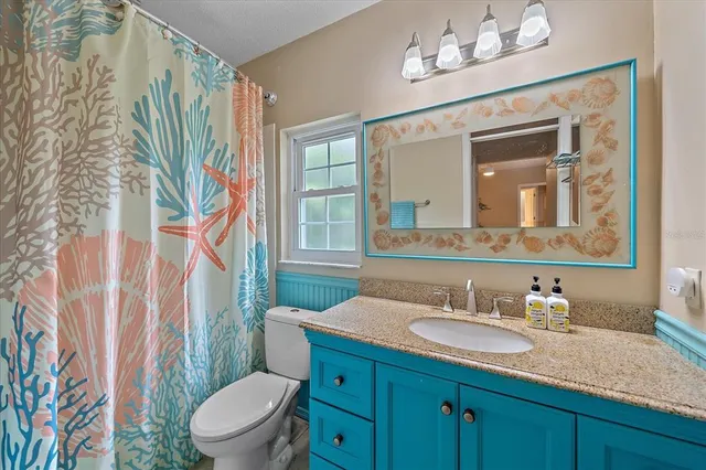 a bathroom with a granite countertop sink a toilet and a mirror