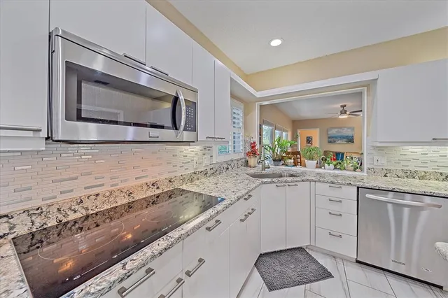 a kitchen with granite countertop white cabinets white stainless steel appliances and a sink