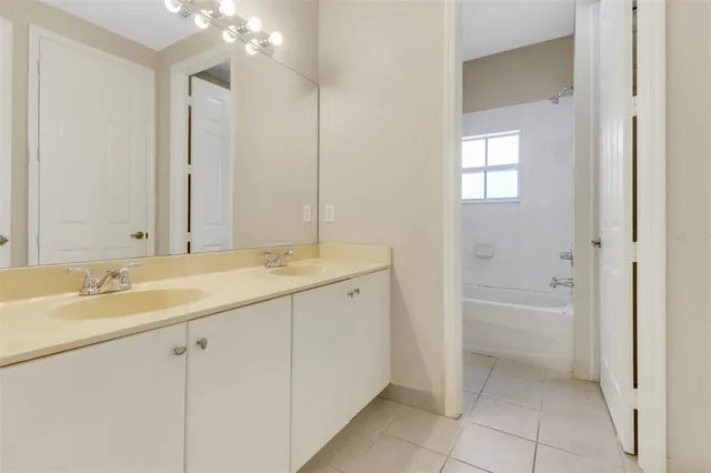 a spacious bathroom with a granite countertop sink a mirror and a bathtub