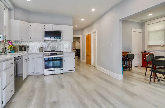 a kitchen with stainless steel appliances granite countertop a stove top oven a sink dishwasher and a refrigerator with wooden floor