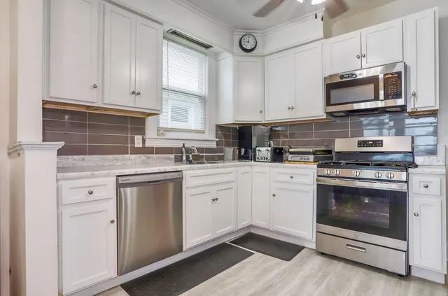 a kitchen with white cabinets stainless steel appliances and sink