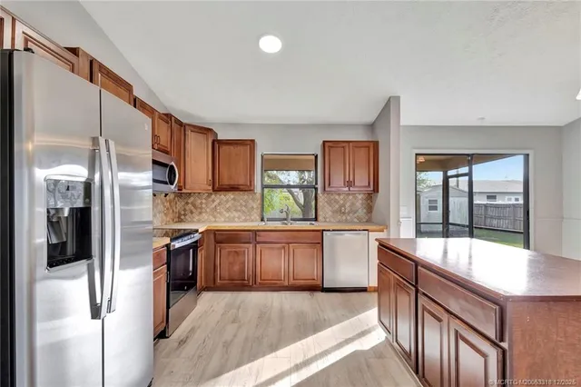a large kitchen with stainless steel appliances granite countertop a refrigerator and a stove top oven