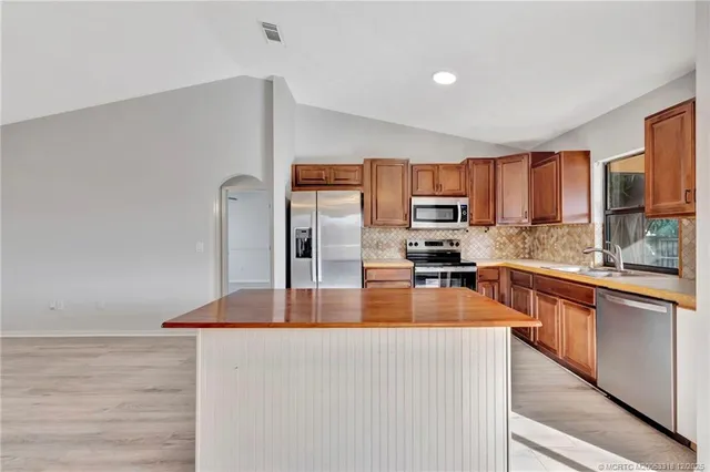 a kitchen with stainless steel appliances granite countertop a refrigerator a stove top oven a sink and dishwasher