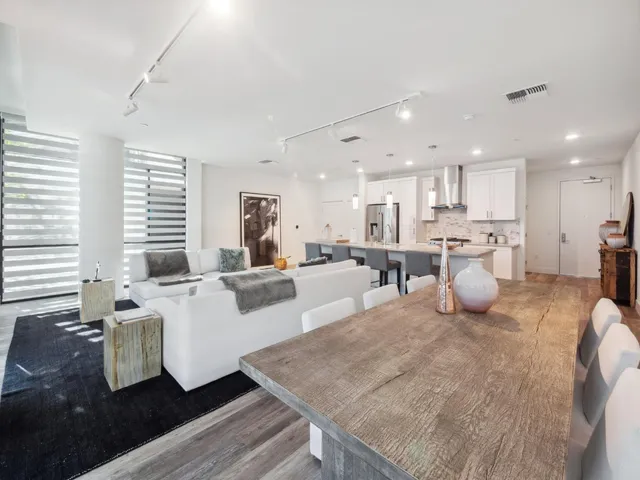 a living room with furniture kitchen view and a large window